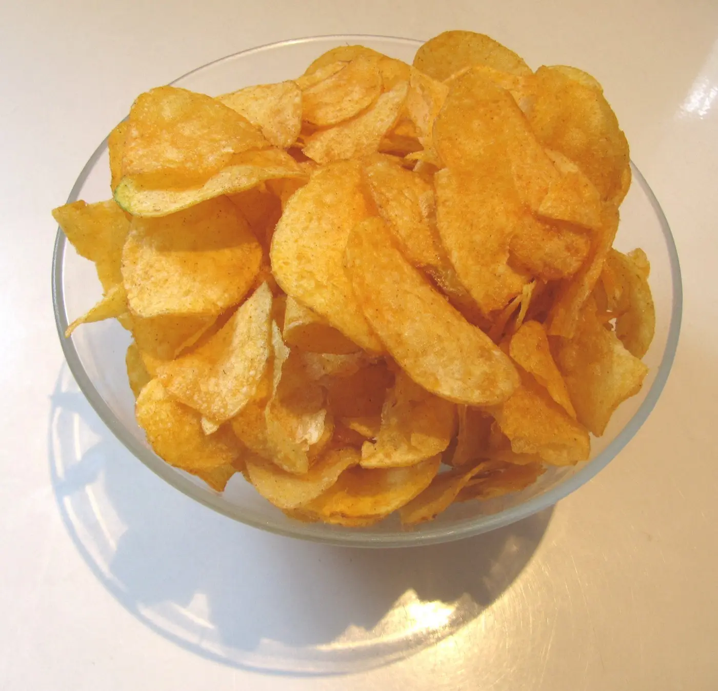 Glass bowl full of golden potato crisps