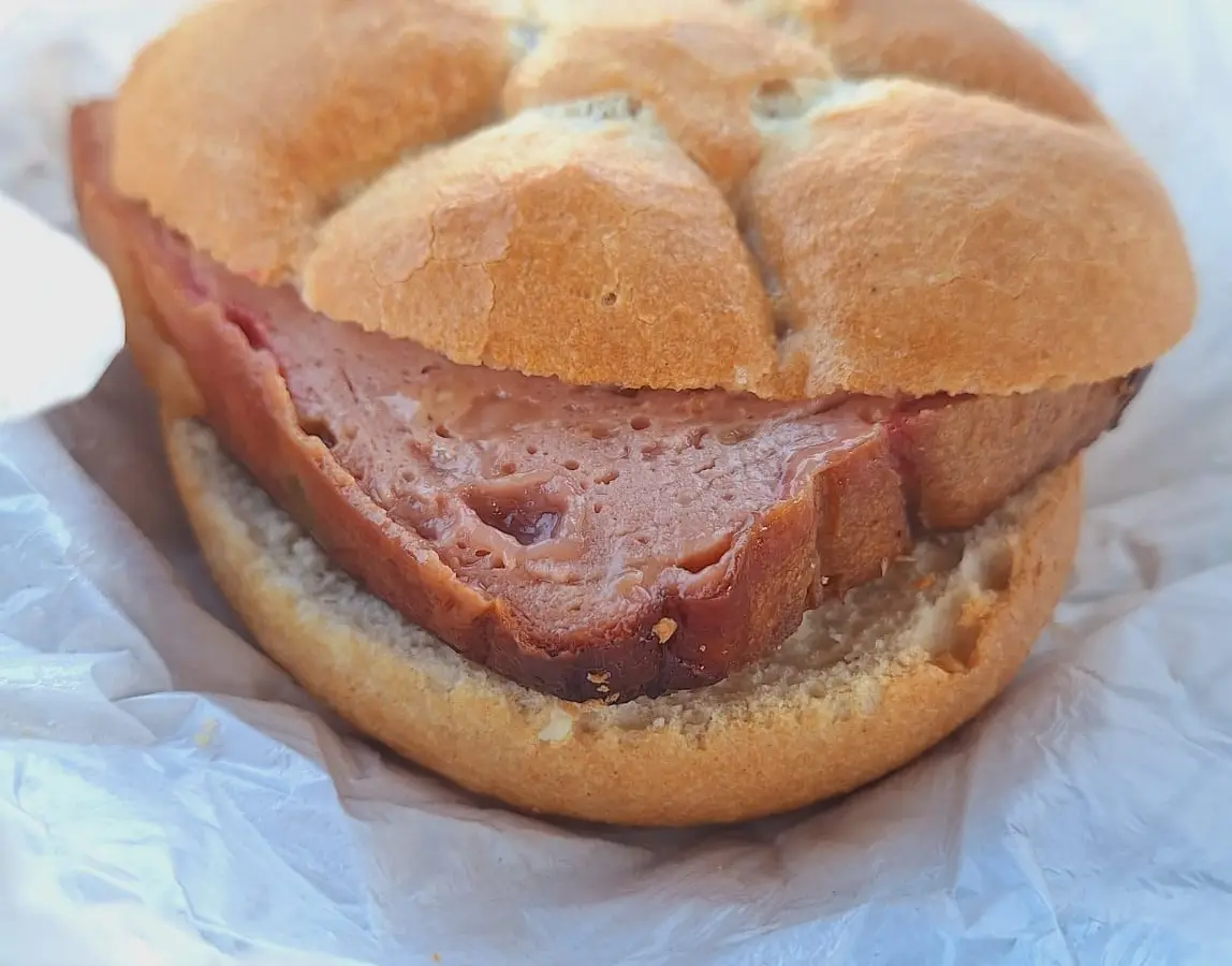 Leberkässemmel: dicke Scheibe Leberkäse in einer Semmel auf Papier